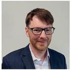 A person wearing glasses and a suit AI-generated content may be incorrect.